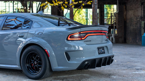 Rear three-quarter view showing the widebody arches and carbon spoiler